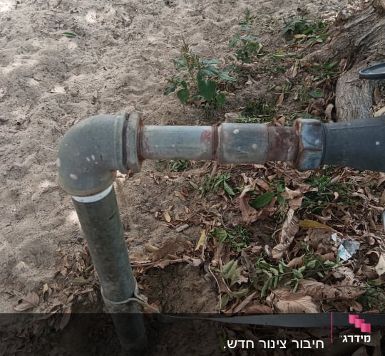 צינור מתכת עם חיבורי ברזל חלודים באדמה